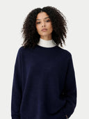Woman wearing a navy sweater over a white collar on a light gray background #color_navy