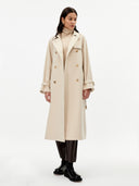 front view of a woman wearing a beige double breasted cashmere trench coat over a sweater and dark pants on a gray background #color_beige