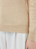 close up of a beige sweater sleeve and white pants #color_beige