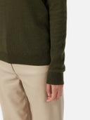 close up of a dark green sweater sleeve and beige leather pants #color_capulet-olive