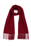 flat lay of a wrapped red fringed scarf on a light gray background bordeaux