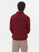 close up back view of a man wearing A red sweater long sleeves, beige pants on a light gray background #color_bordeaux