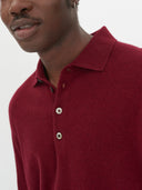 close up of a man wearing a red polo sweater on a light gray background #color_bordeaux