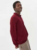 close up side view of a man wearing A red cashmere polo sweater with a collar, buttons, and long sleeves, beige pants on a light gray background #color_bordeaux