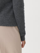 close up back view of a gray sweater sleeve and white pants on a white background  #color_stone-gray