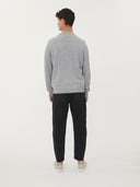 back view of a man standing, a gray cardigan and black jeans on a light gray background.  #color_vapor-blue