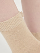 close up of beige colored minimal socks with a small brand label "GOBI" on a light gray background #color_beige