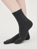 person wearing dark gray sock with a small label on a light gray background #color_charcoal