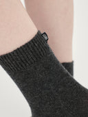 close up of a person wearing dark gray socks with a small label "GOBI" on a light gray background #color_charcoal