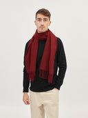 man wearing a red fringed scarf over a black sweater and beige pants bordeaux