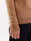 close up of an almond color sweater with long sleeves and black pants. #color_sheepskin