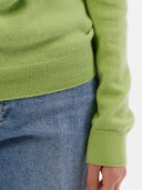 close up of a green long sleeve sweater and jeans #color_jade-lime