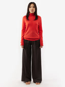 front view of a woman wearing a red turtle neck sweater and dark pants #color_fiesta