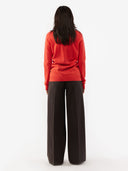 back view of a woman wearing a red turtle neck sweater and dark pants #color_fiesta