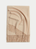 A folded cream-colored knit throw blanket with fringed edges, displayed on a clean white background.