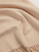 close up of a beige scarf with fringe.