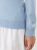 close up of a blue sweater sleeve detail and a white skirt #color_light-blue