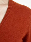 close up of a red-orange cardigan neck on a light gray background #color_sugar-almond